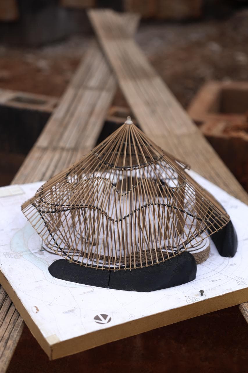A bamboo scale model resting on architectural drawings