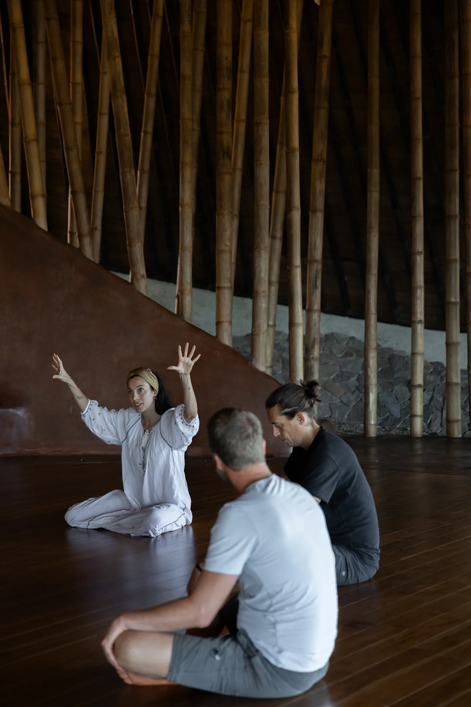 Residents moving together in the maloca, bamboo screen behind them