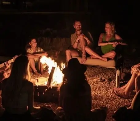 People sitting in a circle around a campfire at night